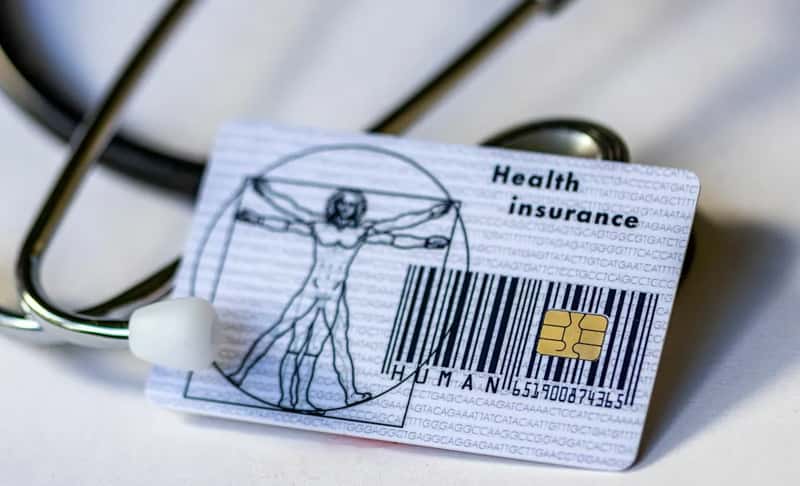 A Folder of Health Insurance Papers Sits Near the Suitcase (Image Credits: Unsplash)