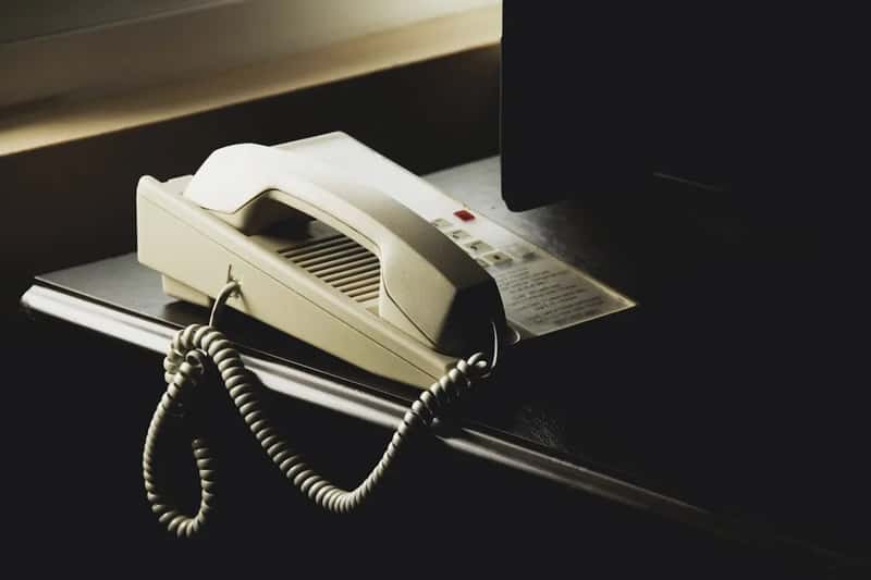 Using the in-room phone instead of your own device (Image Credits: Unsplash)