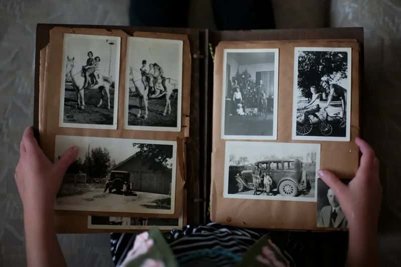 Filling photo albums with printed vacation pictures (Image Credits: Unsplash)