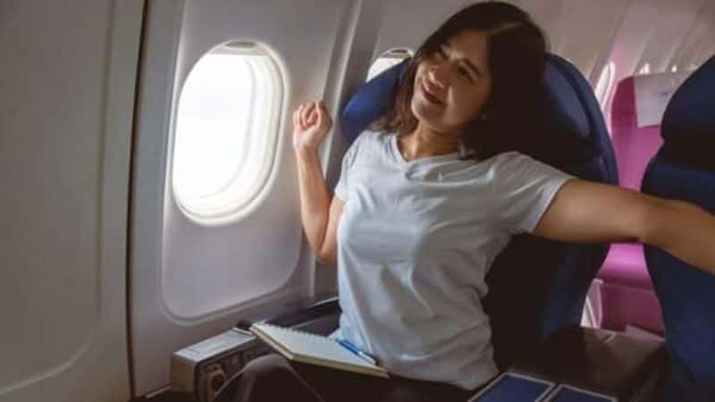 A woman plane passenger relaxing and stretching after longtime airplane travel.