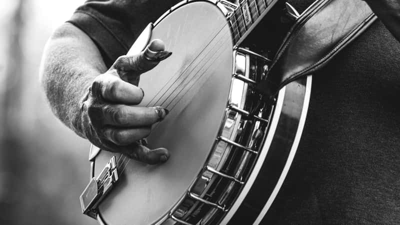 male playing five string banjo outside in monochrome black and white close-up of hand and fingers bluegrass music