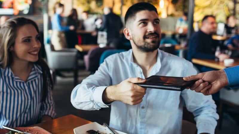 A couple tipping their waitress at a restaurant.