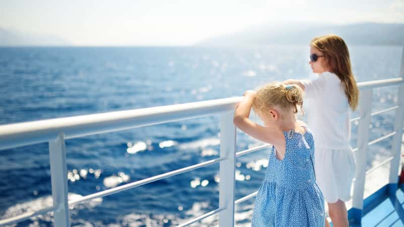 Adorable young girls enjoying ferry ride staring at the deep blue sea. Children having fun on summer family vacation in Greece. Kid sailing on a boat.