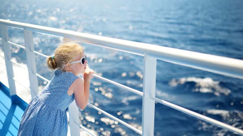 Adorable young girl enjoying ferry ride staring at the deep blue sea. Child having fun on summer family vacation in Greece. Kid sailing on a boat.