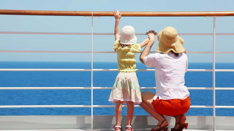 behind mother and her daughter standing on deck of yacht and they look far aboard