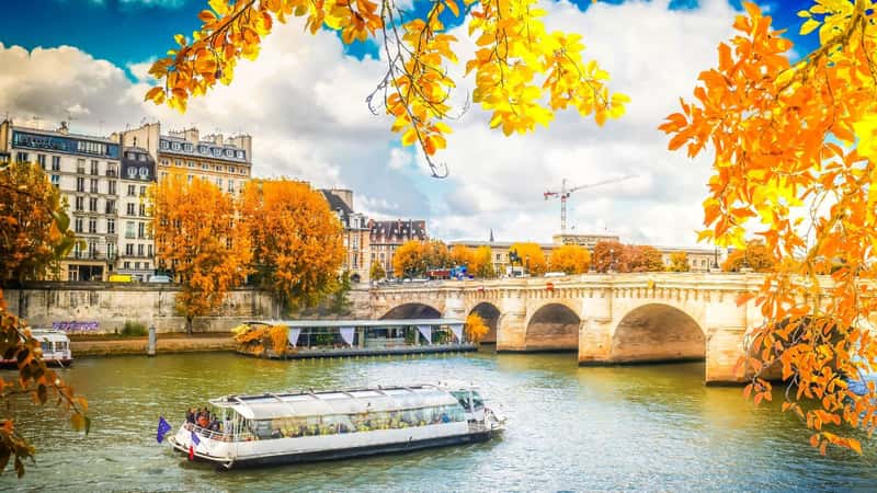 Pont Neuf and river Seine waters with cruise ship, blue sky with clouds, Paris at autumn, France with sunshine