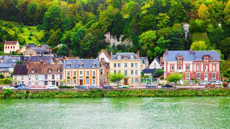 The coast of the Seine River in France in the suburbs of Rouen with beautiful private houses and dense green vegetation and mountains.