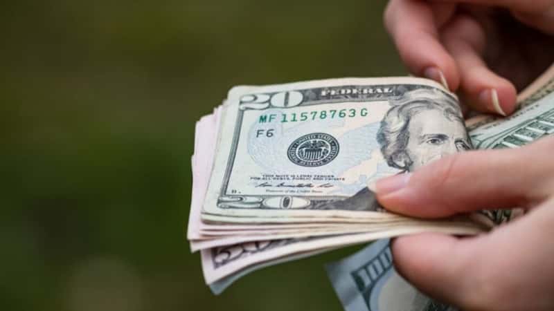 Selective focus on detail of USD banknotes. Counting or giving United States Dollars banknotes. World money concept, inflation and economy concept