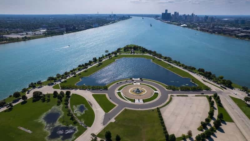 Aerial view of the Belle Isle island and the surrounding blue Detroit River with Detroit skyline in the background. Shot in Detroit, Michigan, United States.