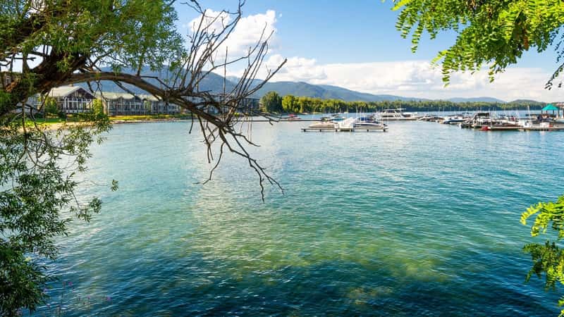 View from the Sandpoint City Beach Park of Lake Pend Oreille waterfront resorts and condominiums with marinas full of boats on a summer day in Sandpoint, Idaho.