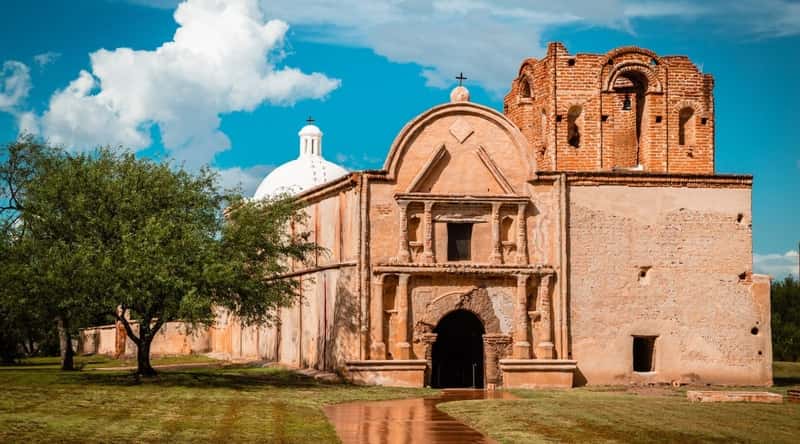 A captivating view of the Tumacacori National Historical Park. The photo shows the well-preserved ruins of the Spanish mission, built of sand-colored stone. The stone archways, bell tower, and intricate details of the mission architecture stand as a testament to centuries of history.