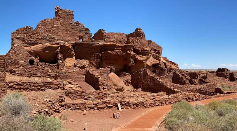 An awe-inspiring photo of Wupatki National Monument. The image captures the ancient Puebloan ruins, composed of red sandstone, amidst the arid, high desert landscape. The image showcases the intricate masonry of the ruins, illustrating the architectural ingenuity of the ancient inhabitants.