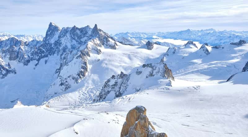 Aiguille du Midi in Chamonix, France. This iconic mountain peak, part of the Mont Blanc massif, stands tall against the azure sky, its majestic summit reaching dizzying heights. The jagged peaks of neighboring mountains surround Aiguille du Midi, creating a dramatic alpine panorama.