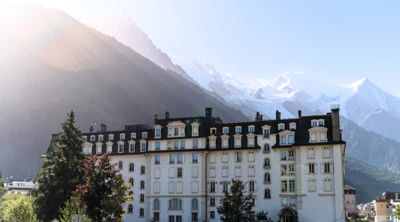 The Alpine Museum in Chamonix, France, stands against the backdrop of the majestic French Alps. The museum boasts beautiful architecture, characterized by a dark-colored roof, and is surrounded by ample greenery.