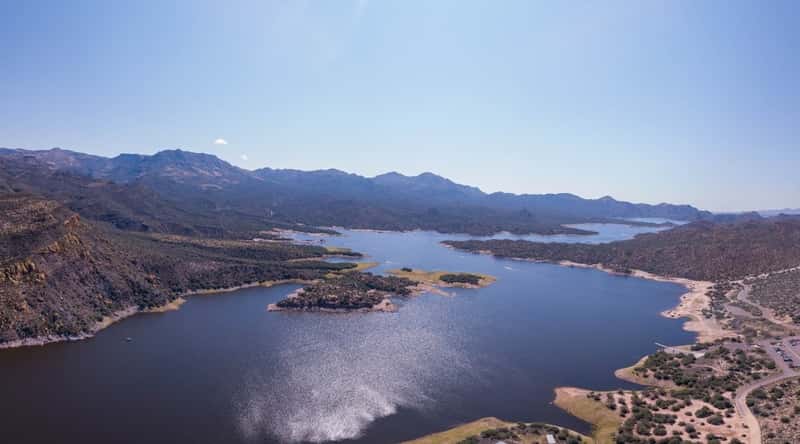  A photograph capturing Bartlett Lake in Arizona, featuring the lake's waters against a backdrop of surrounding desert landscape. The shoreline exhibits typical desert vegetation. Cliffs and hills surround the lake, contributing to the arid scenery. 