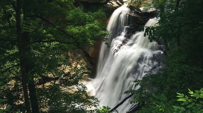 Brandywine Falls is a picturesque waterfall located in the Cuyahoga Valley National Park in Ohio, USA, featuring a 65-foot drop and surrounded by beautiful foliage and rock formations.