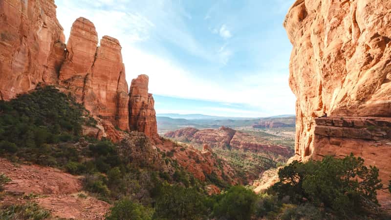 A view from the top of Cathedral Rock Trail in Sedona, Arizona. The image captures the scenic viewpoint at the summit, showcasing the rugged terrain and red rock formations characteristic of the area. The viewpoint offers a panoramic perspective of the surrounding landscape, with sparse vegetation dotting the rocky terrain.