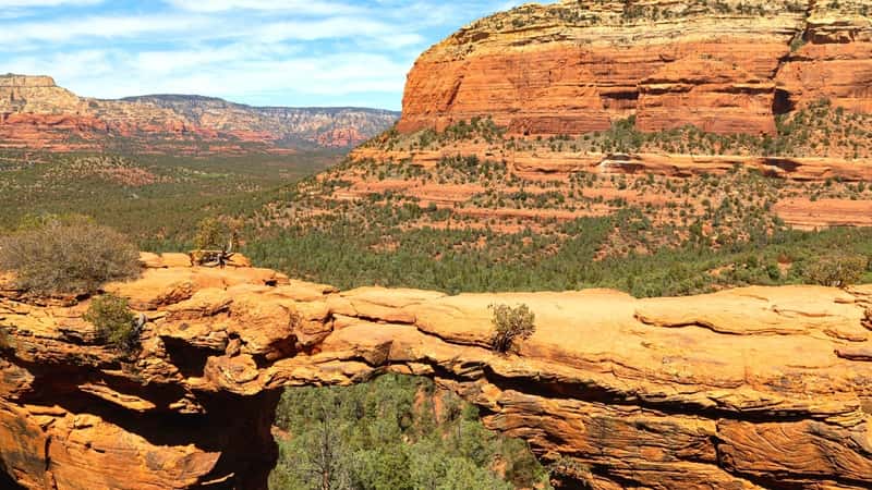 A photograph depicting Devil’s Bridge Trail, showcasing the natural terrain and hiking path. The trail features rocky terrain, sparse vegetation, and the distinct rock formations typical of the area. 