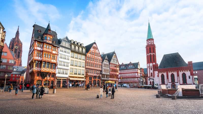 In Frankfurt, Germany, Romerberg Square showcases the Old St. Nicholas Church and colorful half-timbered buildings. The church boasts a historic architectural style with intricate details. Surrounding it are traditional half-timbered buildings painted in a variety of vibrant colors.