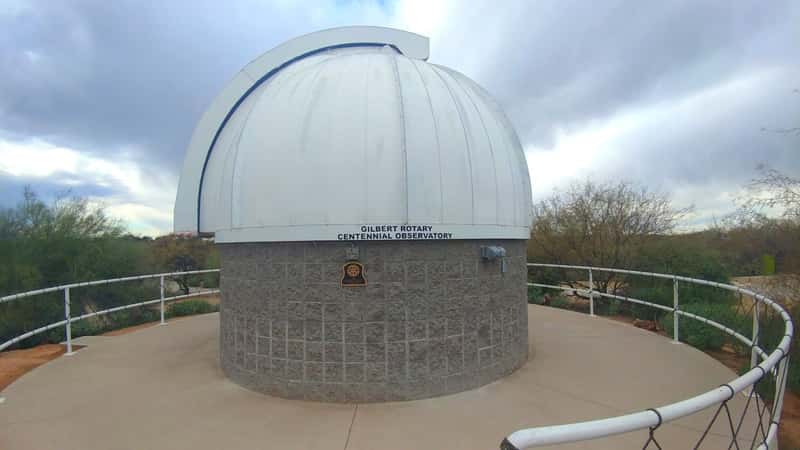 A close-up view of the Gilbert Riparian Observatory. The image showcases the observatory's architectural details, including its structure and design elements. The observatory appears to be situated within a natural setting, surrounded by trees and vegetation.