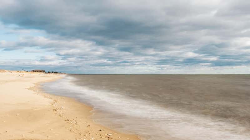 The image showcases a landscape view of Hammonasset Beach State Park in Madison, Connecticut, under a cloudy sky. 