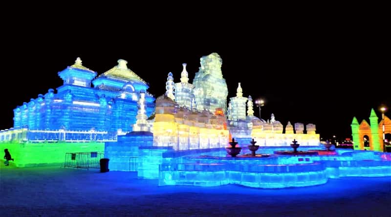 The photograph depicts the annual Harbin International Ice and Snow Festival in Harbin, China. Sculpted ice castles and palaces are showcased as prominent features of the festival. The structures are meticulously crafted from ice.
