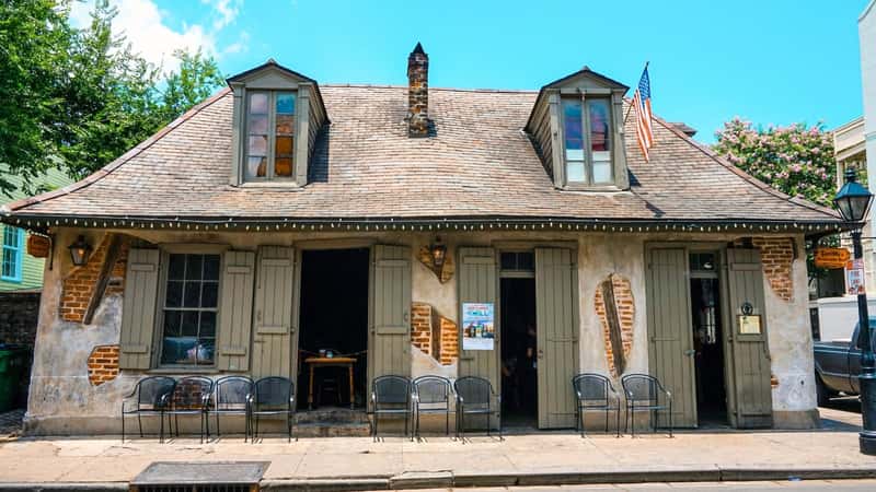 Lafitte's Blacksmith Shop Bar in the French Quarter of New Orleans, Louisiana, is a historic building with weathered brick walls and wooden shutters.