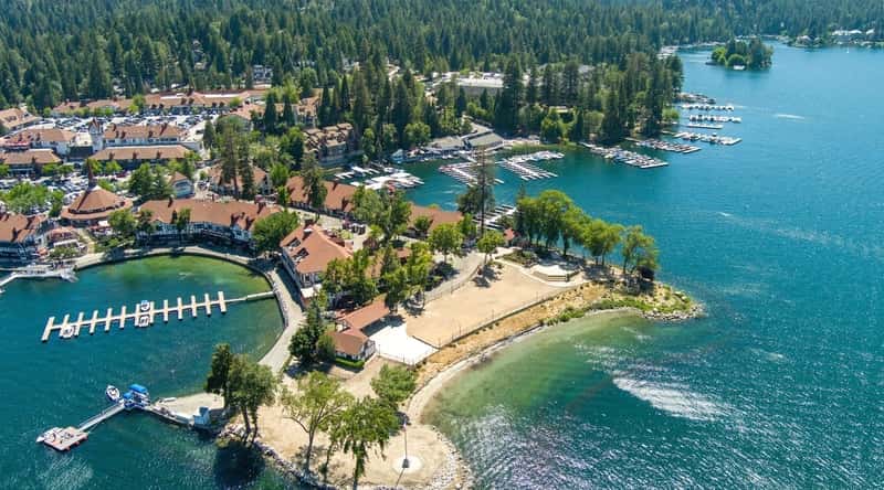 A photograph capturing Lake Arrowhead, a reservoir in the San Bernardino Mountains of Southern California. The image showcases the lake's expanse surrounded by forested landscapes. Boats and recreational activities are visible on the water.