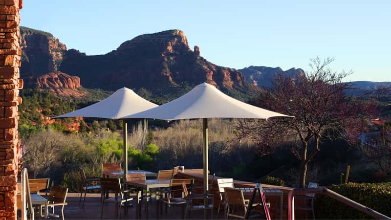 A photograph depicting a local cafe in downtown Sedona, Arizona, with mountain views in the background. The mountainous landscape provides a scenic backdrop, enhancing the ambiance of the cafe.
