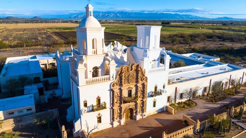 Mission San Xavier del Bac, located in the Tohono O'odham Nation Indian Reservation near Tucson, Arizona, USA. The mission stands out with its distinctive Spanish colonial architecture, characterized by adobe walls, red clay roof tiles, and intricate details.