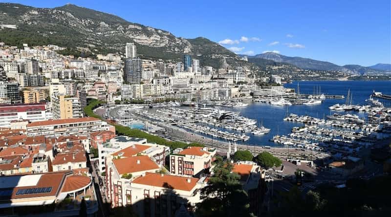 A photograph capturing the allure of Monaco Harbor, nestled against the stunning backdrop of the French Riviera. The image showcases the azure waters of the Mediterranean Sea, gently cradling an array of luxurious yachts and sailboats.