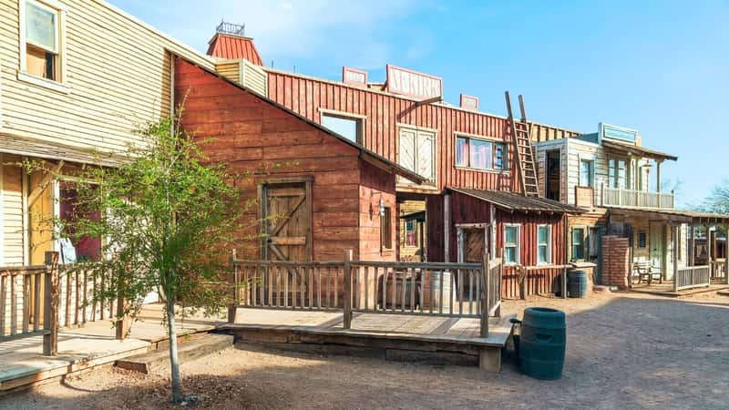 Old Tucson, Arizona, USA, wooden buildings stand prominently against the desert landscape. These buildings are characterized by their two-story structure, reflecting the traditional architectural style of the region. The color palette of the buildings is primarily earthy, blending with the natural tones of the arid surroundings.