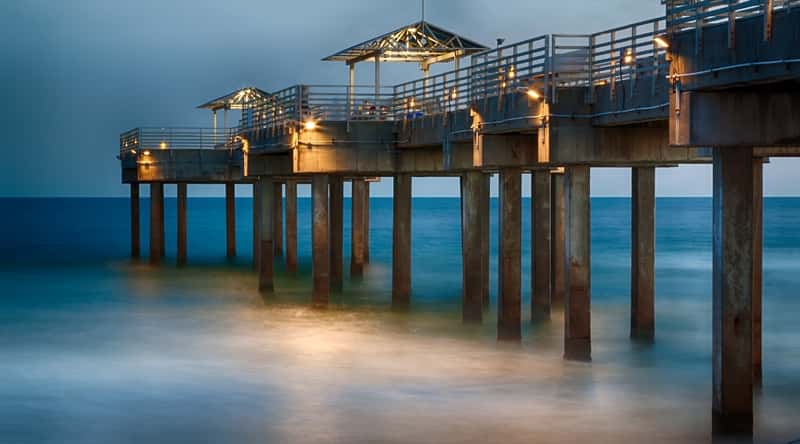 The Orange Beach Waterfront Park in Alabama features a beautiful beach and a pier that extends out into the Gulf of Mexico, offering stunning views of the coastline. There are atmospheric restaurants on the pier.