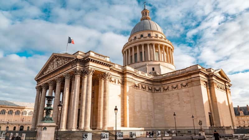 The image captures the Pantheon in Paris, France, showcasing its neoclassical architecture. The building features a dome and Corinthian columns. Its color palette includes shades of beige and gray, reflecting the stone used in its construction. The structure's prominent dome and rectangular base contribute to its recognizable silhouette against the Parisian skyline.