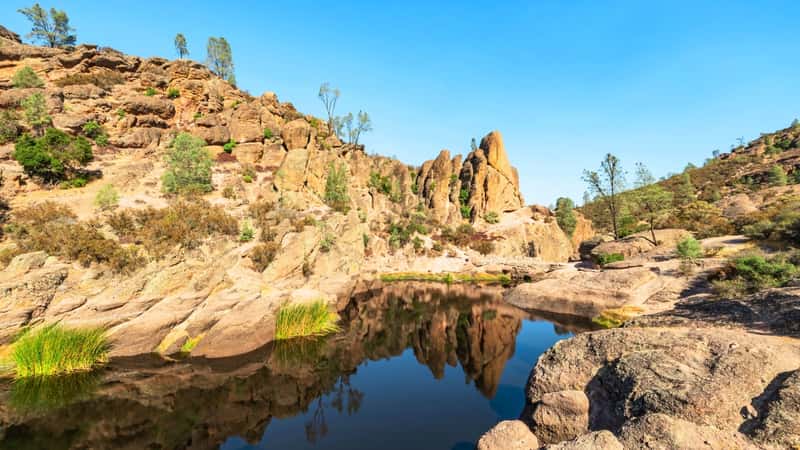 The image depicts Lake Bear Gulch and surrounding rock formations within Pinnacles National Park, located in California. 
