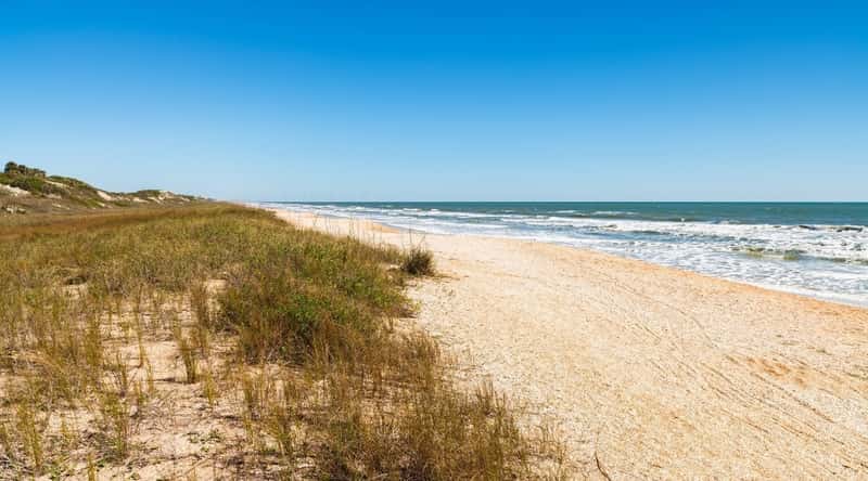 A photograph capturing Ponte Vedra Beach in St. Augustine, Florida. The image showcases the sandy shoreline along the Atlantic coast, with the ocean waves meeting the beach. 