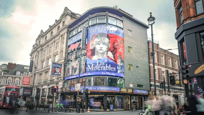 The image features a scene from "Les Miserables" at the Queens Theatre in London's West End.
