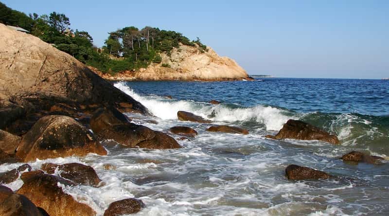 Singing Beach is a beautiful beach located in Manchester-by-the-Sea, Massachusetts, known for its unique sand that creates a musical sound when walked on. Close-up of blue raging waves near rocky reefs.