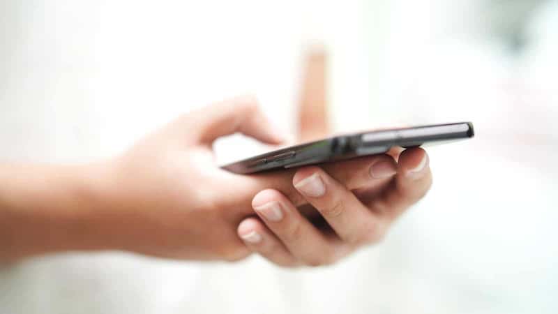 The image captures a close-up view of a man's hands holding a smartphone.