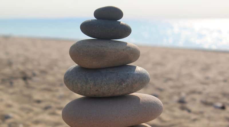 Twelvemile Beach is a scenic spot located in Pictured Rocks National Lakeshore, Michigan, with a long sandy beach, dunes, and towering cliffs. A close-up of rounded gray-brown pebbles stacked one on one, against a blurred background of the beach.