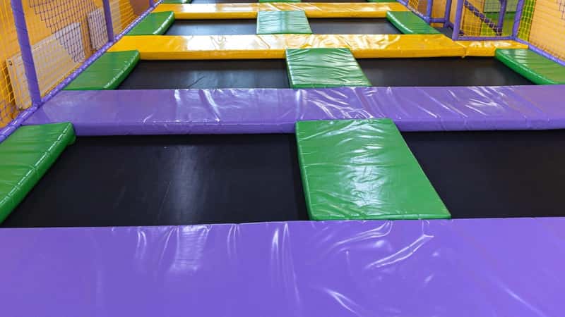 A photograph capturing an empty trampoline room. The image features an unoccupied space with trampolines evenly distributed across the floor.