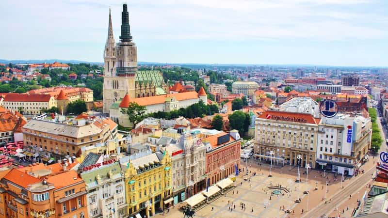 A high-angle photograph capturing the Zagreb skyline in Croatia. The image offers a comprehensive view of the cityscape from an elevated perspective. Recognizable architectural structures and urban features are visible, showcasing the city's layout.