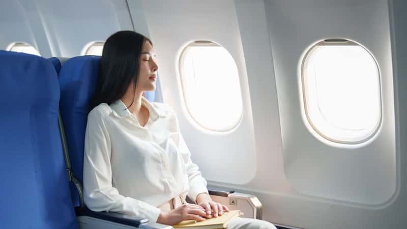 Woman relaxing on a plane with eyes closed.