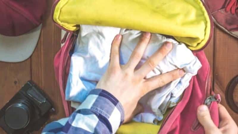 hand packing clothes in the backpack for travel with accessories concept