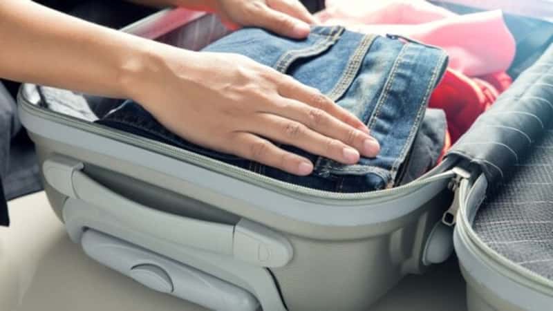 Close up of businesswoman packing clothes into travel bag - Luggage and people concept