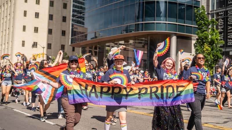 Utah Pride Parade People in Street Holding Happy Pride Rainbow Sign and Flags in Street
