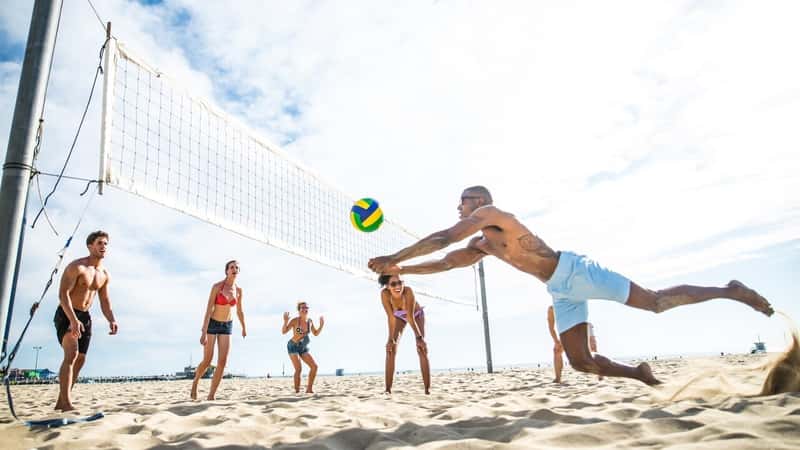 Group of friends playing beach volley.