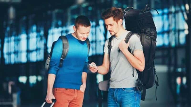 Two friends traveling together. Travelers waiting at the airport departure area for their a flight.