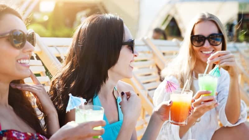 women with drinks on the beach.