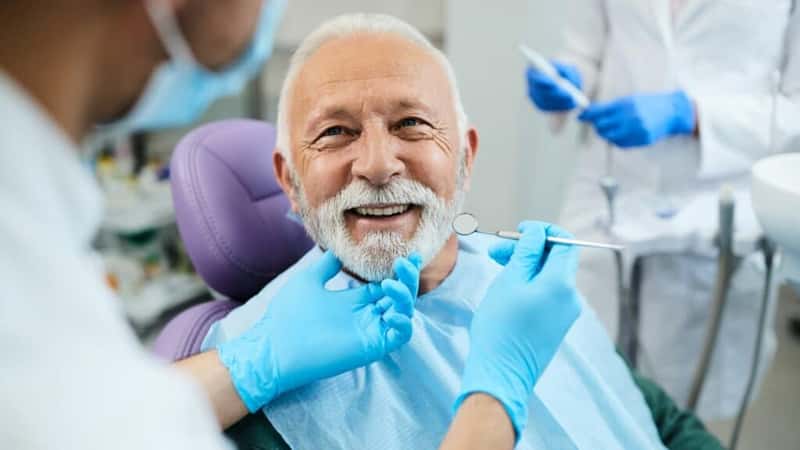 Happy mature man during teeth check-up at dental clinic.